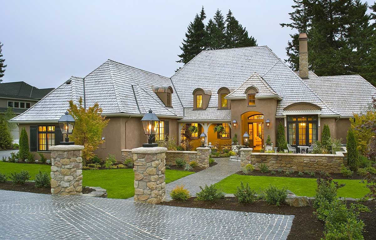 House plan exterior features a stucco finish, multiple gables, dormer windows, and a stone entryway with lanterns.