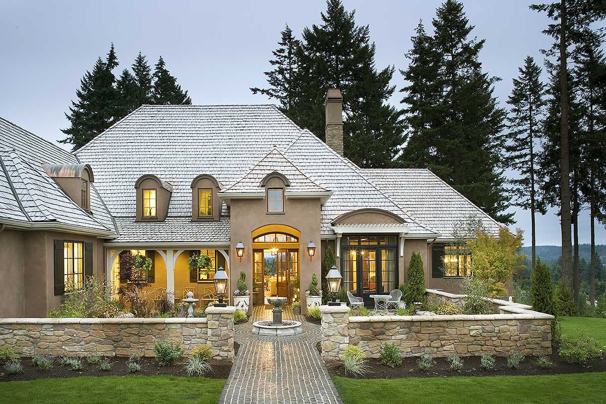 House plan exterior featuring a French Country style, two stories, arched entryway, dormer windows, and stone retaining walls.