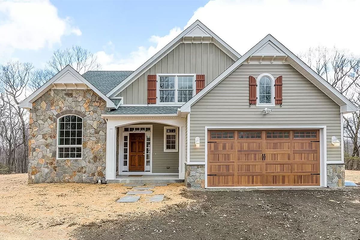 House plan exterior. Craftsman style with a stone facade, gabled rooflines, and a two-car garage with wood doors.