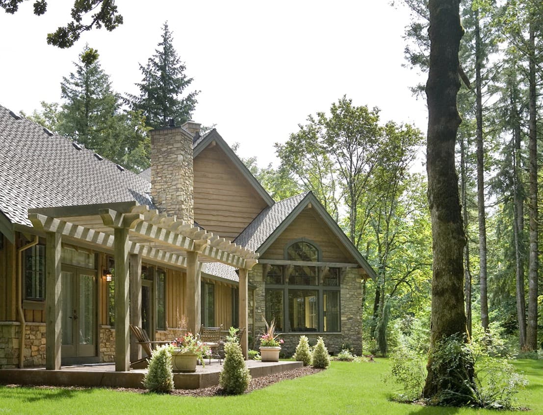 House plan exterior features stone and wood siding, a large stone chimney, and a wooden pergola over a patio.