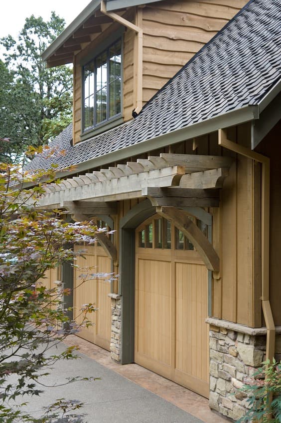 House plan exterior showing multiple wood garage doors with stone bases and a wooden pergola overhead.