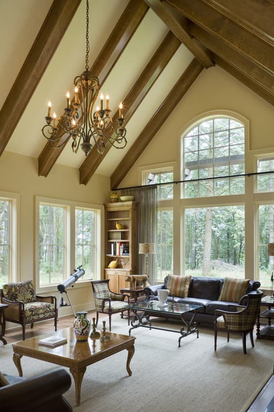 Great room with vaulted ceiling, exposed wooden beams, fireplace, and large arched windows.