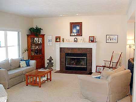 Living room with fireplace, wood cabinet, sofa, coffee table, and rocking chairs.