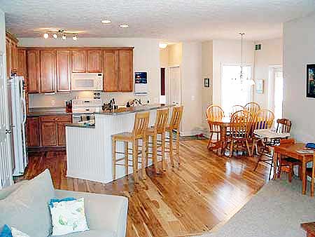 Kitchen with wood cabinets and island bar, adjacent dining area with round table and chairs, and seating area.