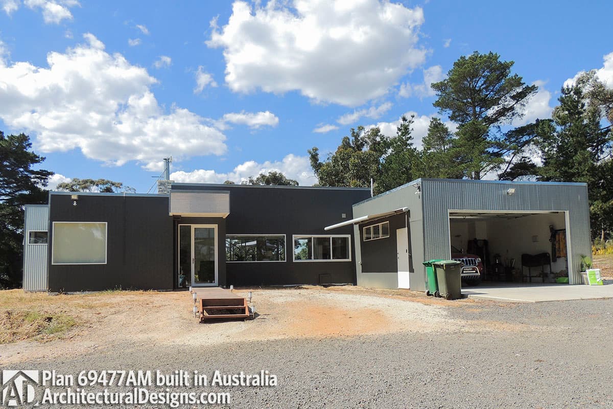 Modern house plan exterior with dark cladding, large windows, and attached two-car garage with metal siding.