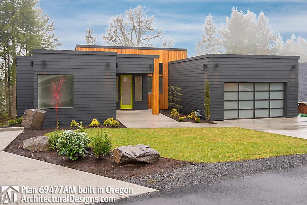 Modern house plan exterior with dark siding, wood accents, a lime green door, and a frosted glass garage door.