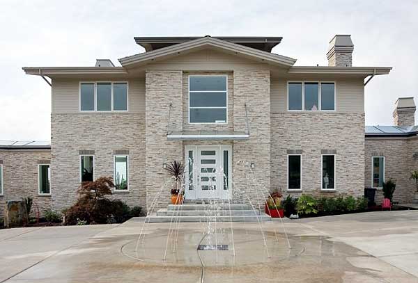 House plan exterior with stacked stone facade, prominent gables, multiple windows, and central double door entry with transom.