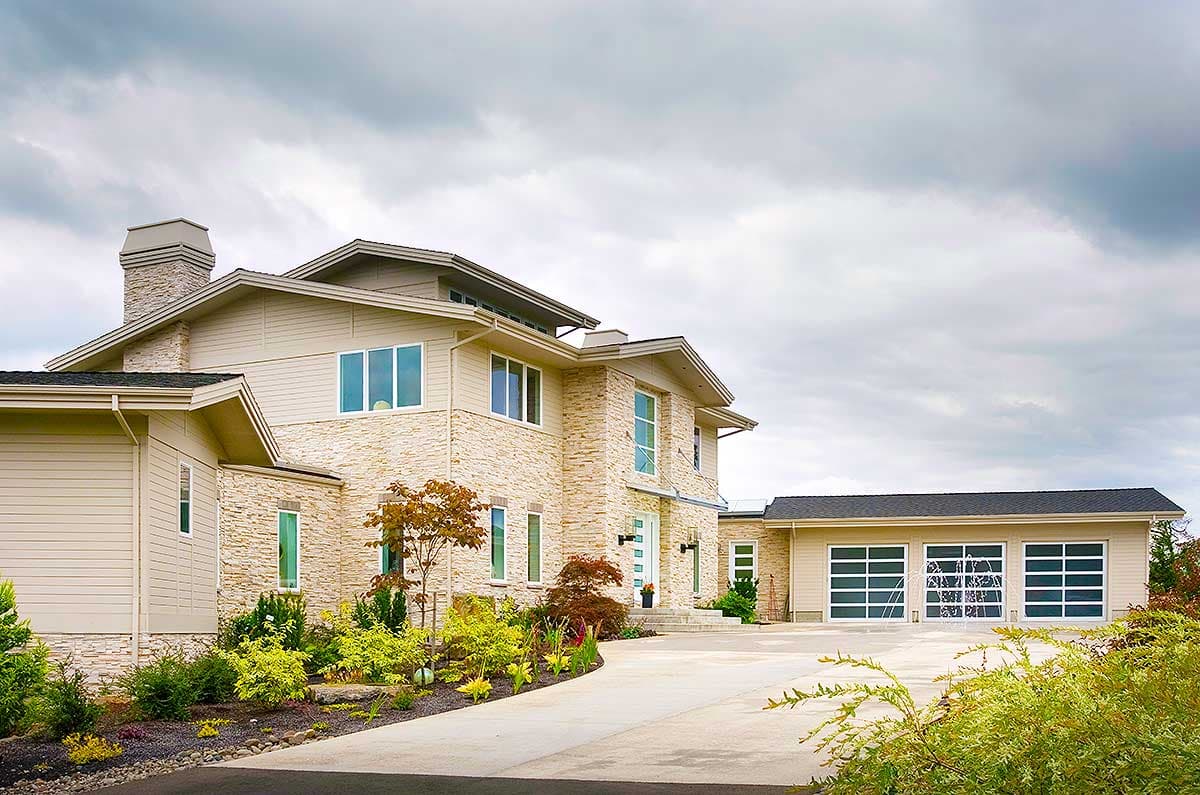 House plan exterior: Modern style, two-story residence with stone facade, multiple gables, and a three-car garage with glass doors.