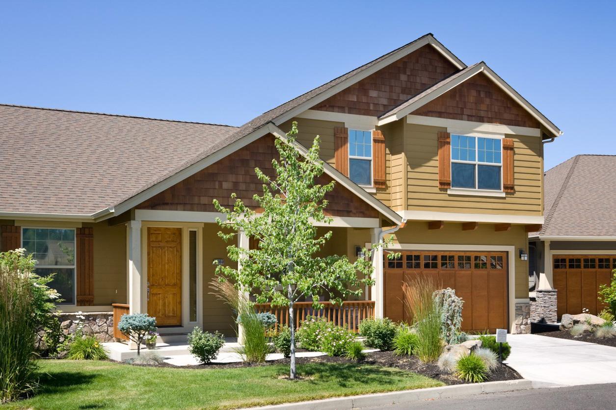Craftsman style house plan exterior with wood shingle gables, covered porch, and dual garage doors.