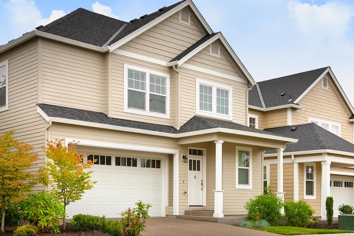 House plan exterior: Two-story home with horizontal siding, gable dormers, covered porch, and a two-car garage.