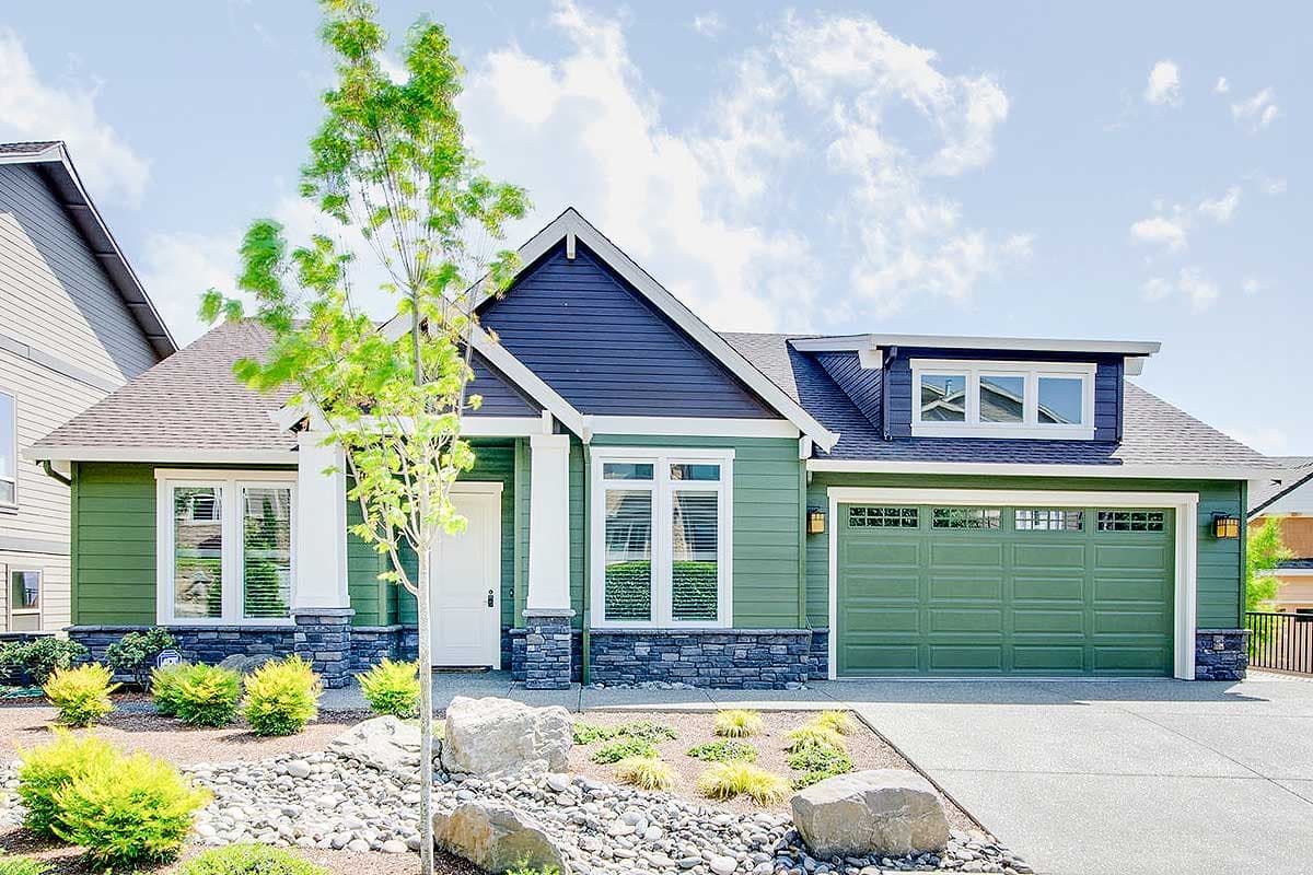 House plan exterior with green siding, stone accents, a covered front entry with columns, and a two-car garage.