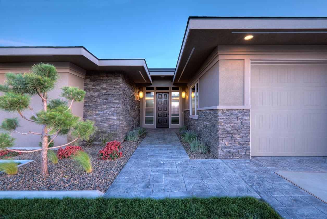 Modern house exterior with stacked stone accents, a covered entryway with double doors, and an attached garage.