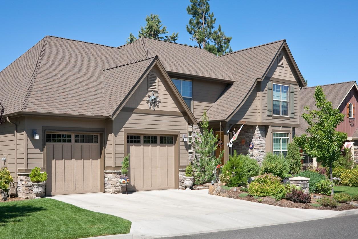 Two-story house plan exterior with a three-car garage, varied gables, stone accents, and a covered entry.
