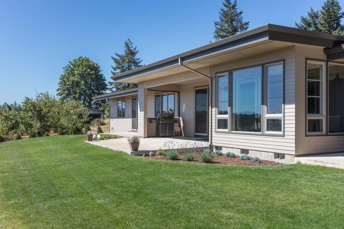Contemporary one-story house plan exterior with a covered patio, large windows, and horizontal siding.