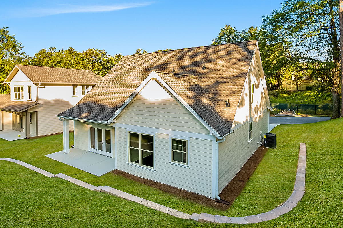 House plan exterior, two stories, showing gable end, covered patio with French doors, and pitched roof.