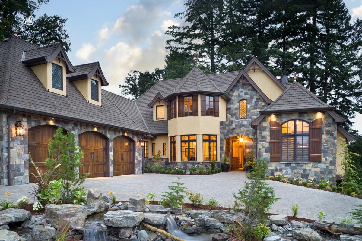 House plan exterior. Two-story, stone and stucco facade, featuring dormers, a turret, and arched garage doors. Stone exterior, multiple rooflines.