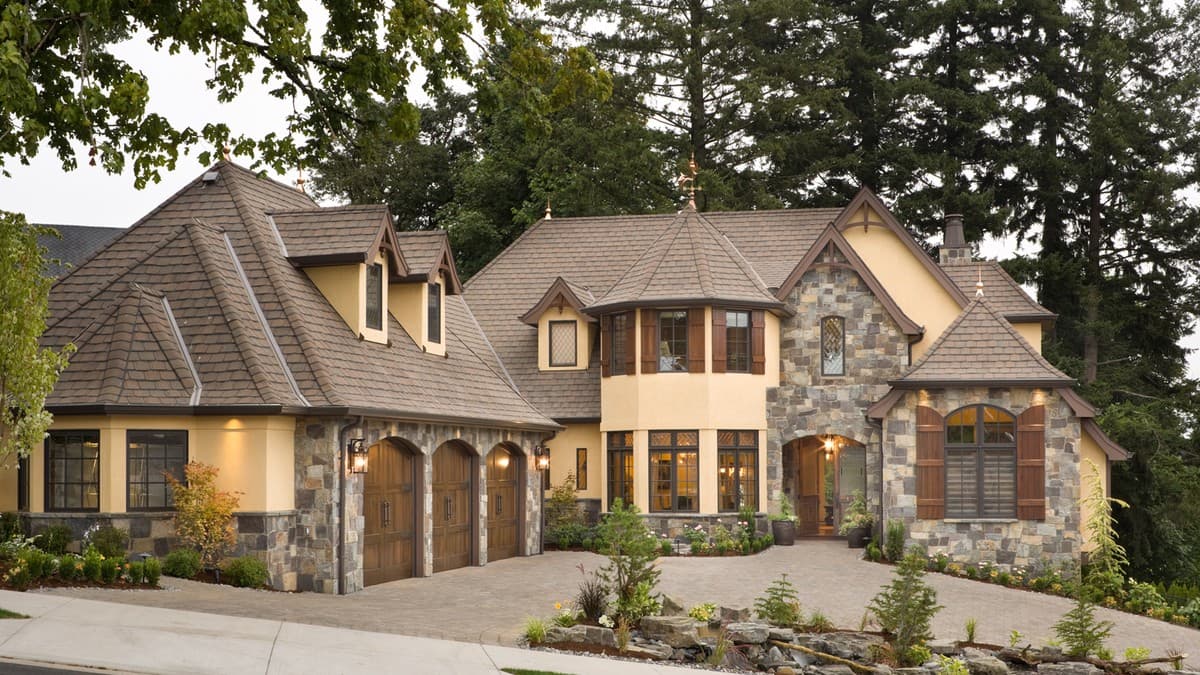 House plan exterior with a stone facade, gables, dormers, a turret, and a three-car garage with arched wooden doors.