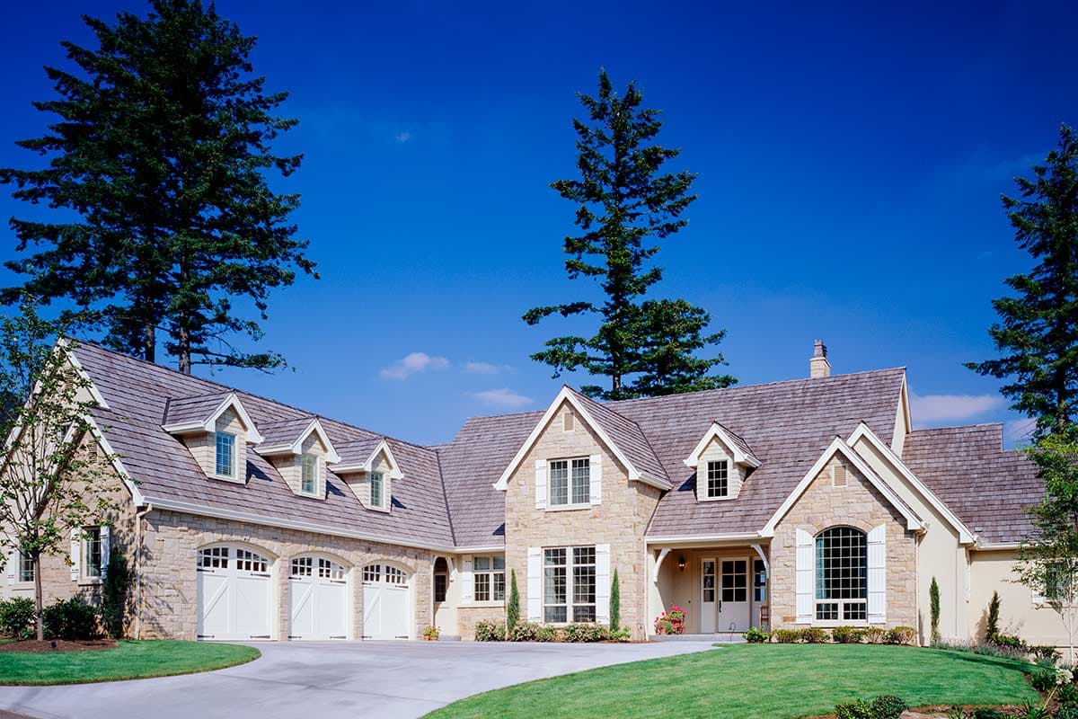 House plan exterior featuring a stone facade, multi-gabled roof, multiple dormers, and a three-car garage.