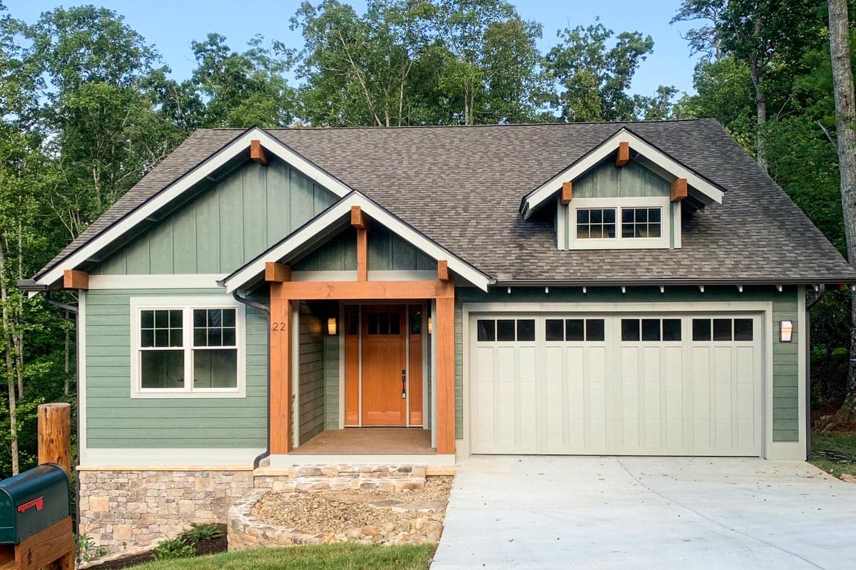 House plan exterior. Craftsman style, one story home with front porch and dormer. Features include gable roof and attached garage.