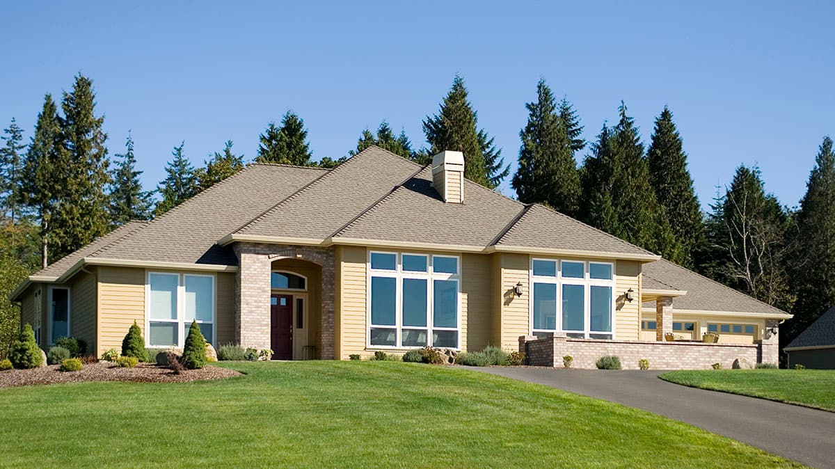 House plan exterior of a single-story home with yellow siding, brick accents, a prominent chimney, and large windows.