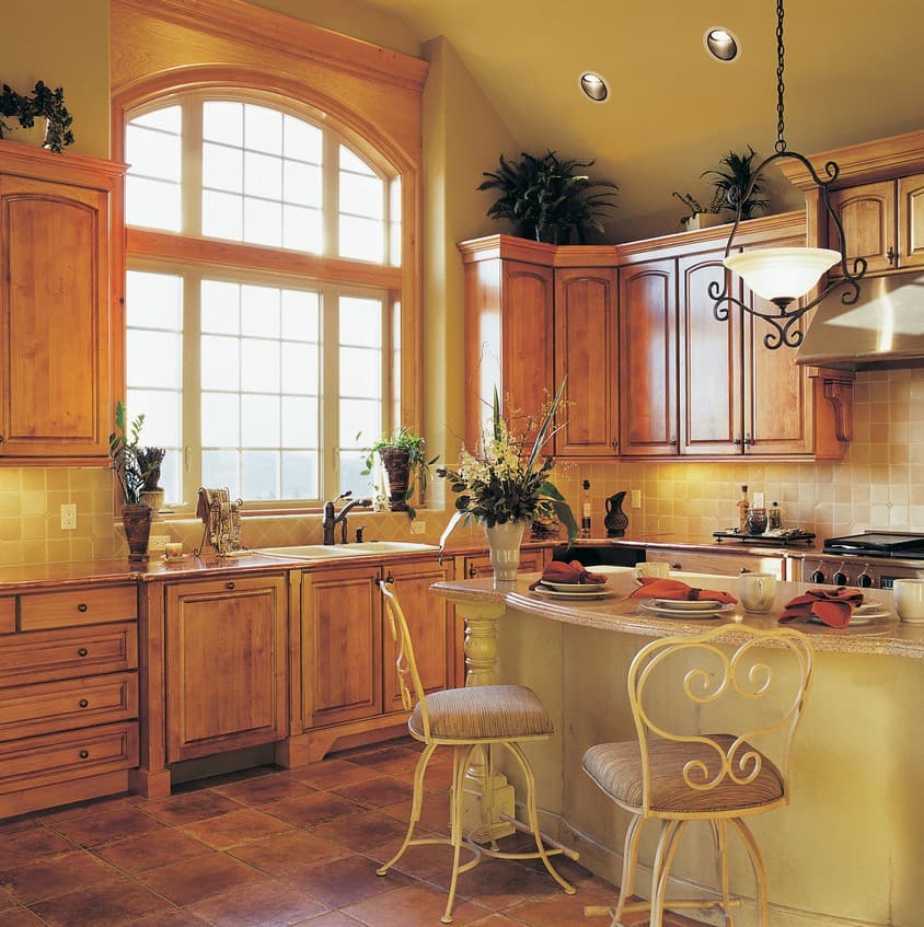 Kitchen with wooden cabinets, granite countertops, a large arched window, and a breakfast bar with stools.
