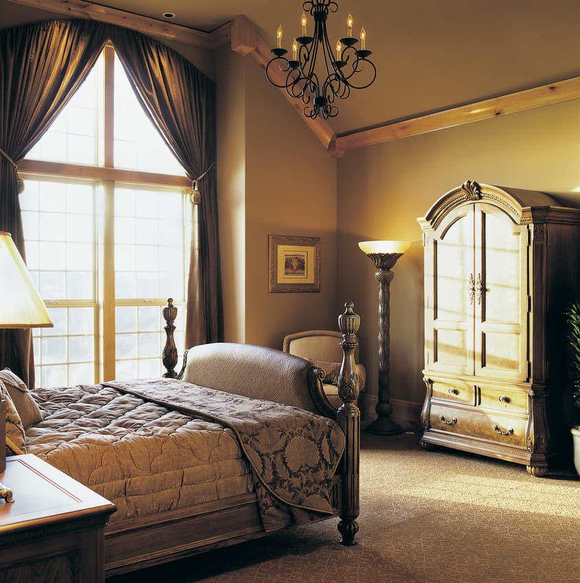 Bedroom with vaulted ceiling, exposed beams, floor-to-ceiling arched window, ornate armoire, and canopy bed.