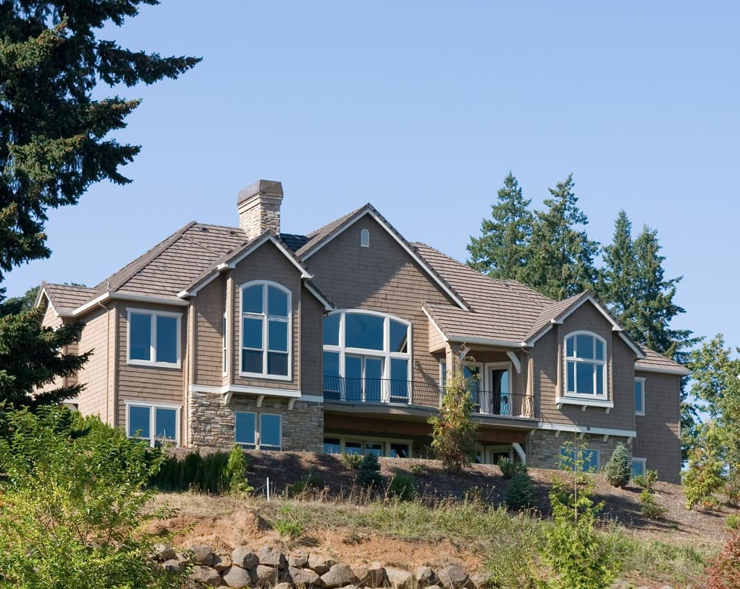 House plan exterior: Two-story home with multiple gables, stone accents, and a covered balcony with wrought iron railing.