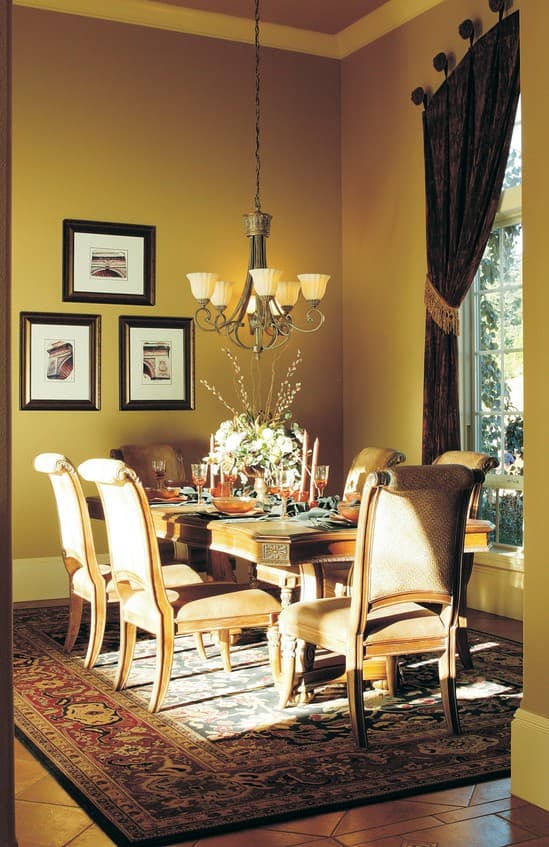 Dining room with a large table set for a meal, ornate chairs, a chandelier, and artwork on the wall.