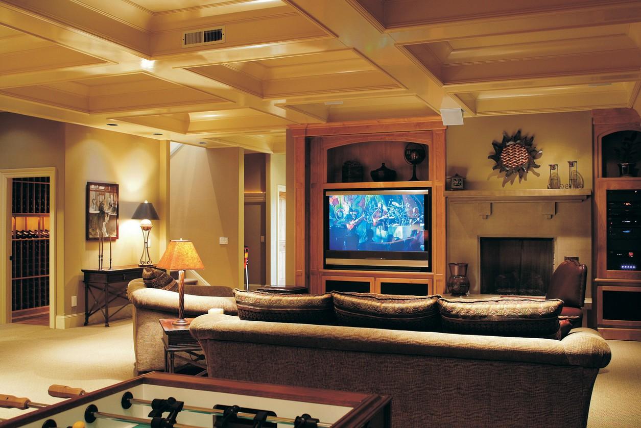 Living room with coffered ceiling, fireplace, entertainment center with large TV, and wine storage.