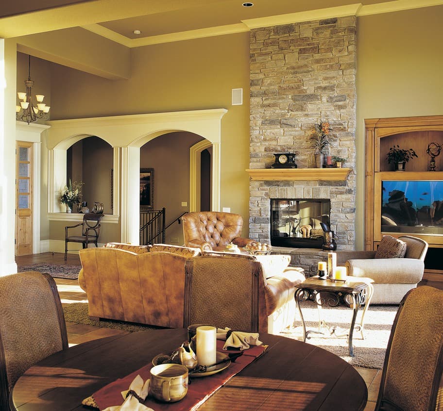Interior view of a living room with a stone fireplace, arched entryways, and a built-in entertainment center.