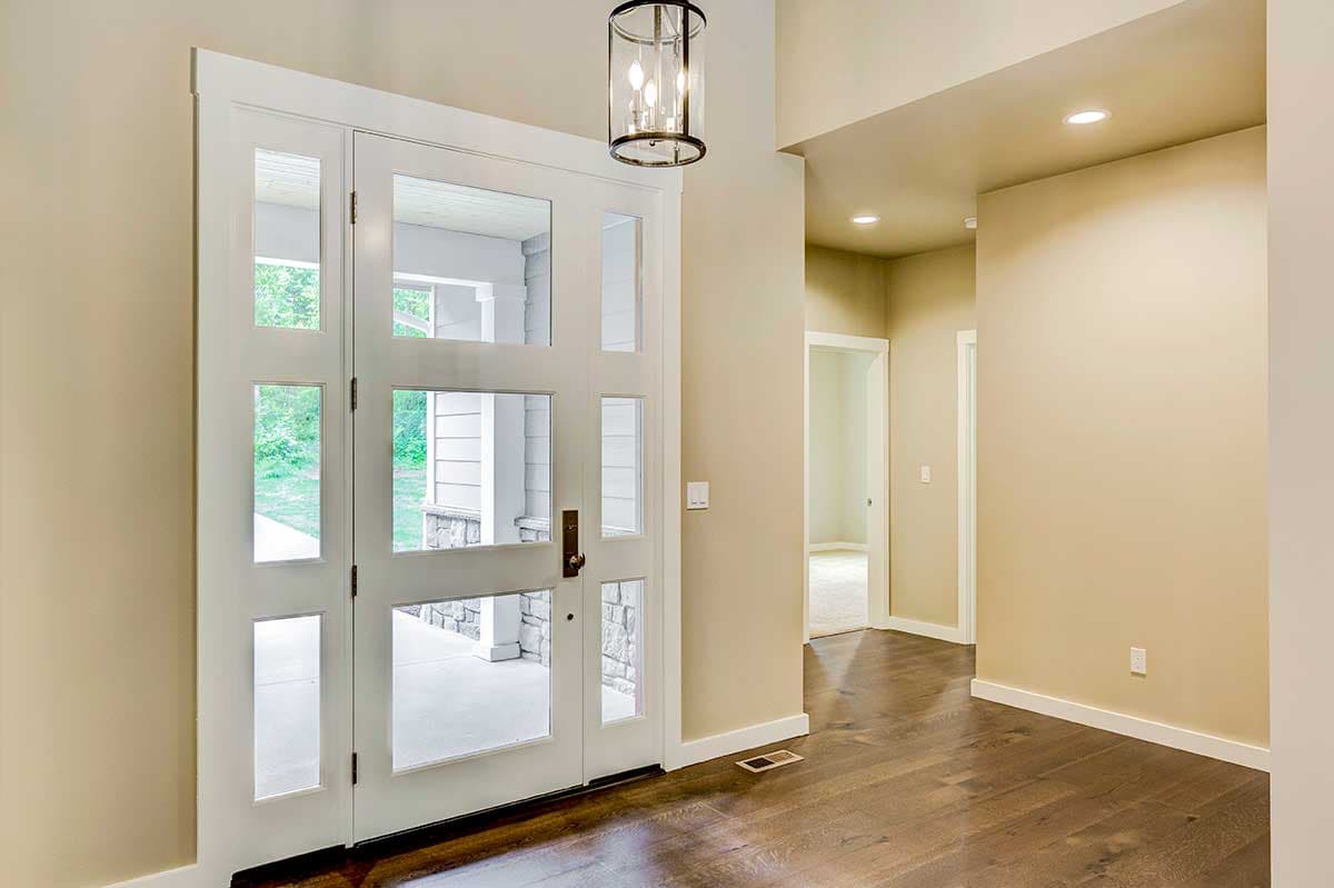 Entryway featuring a double glass door with sidelights, pendant light, and dark wood floors leading to interior rooms.