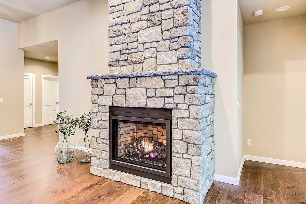 Great room with a floor-to-ceiling stone fireplace and a dark metal surround. Hardwood floors visible.