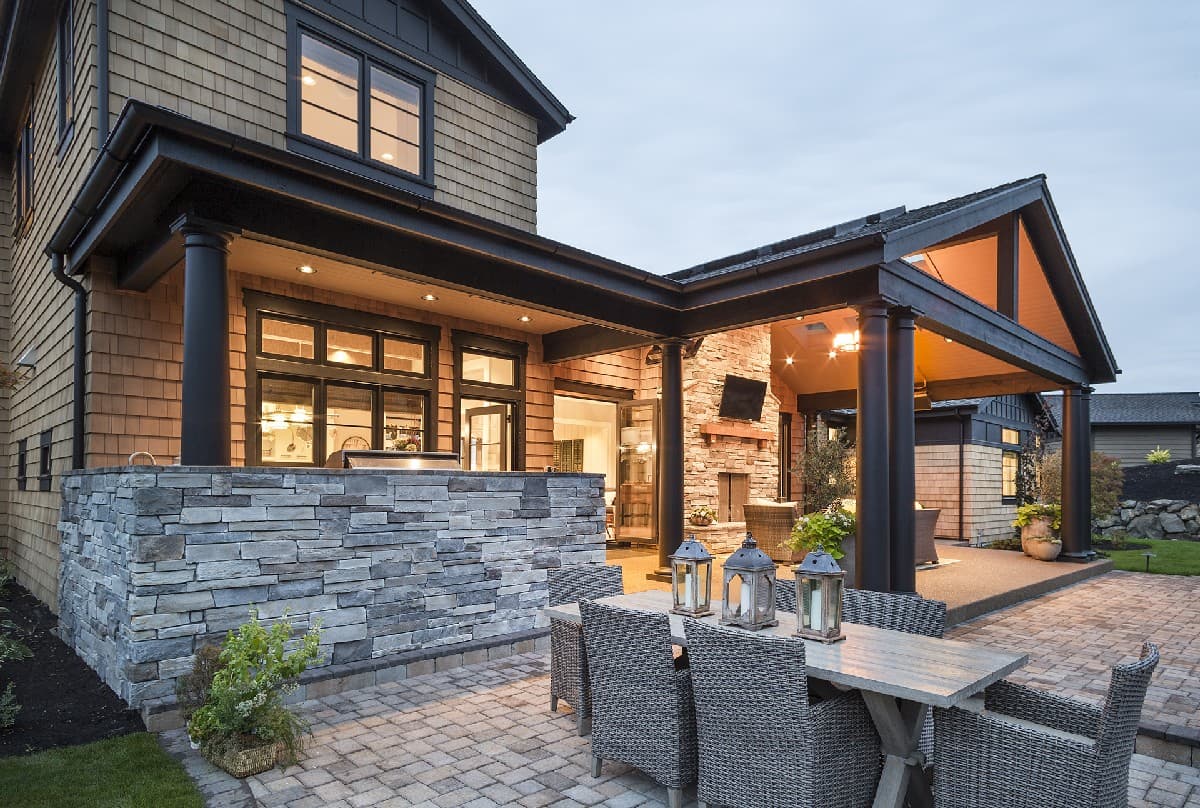 House plan exterior with stone base, covered patio with fireplace, outdoor kitchen, and dining area.
