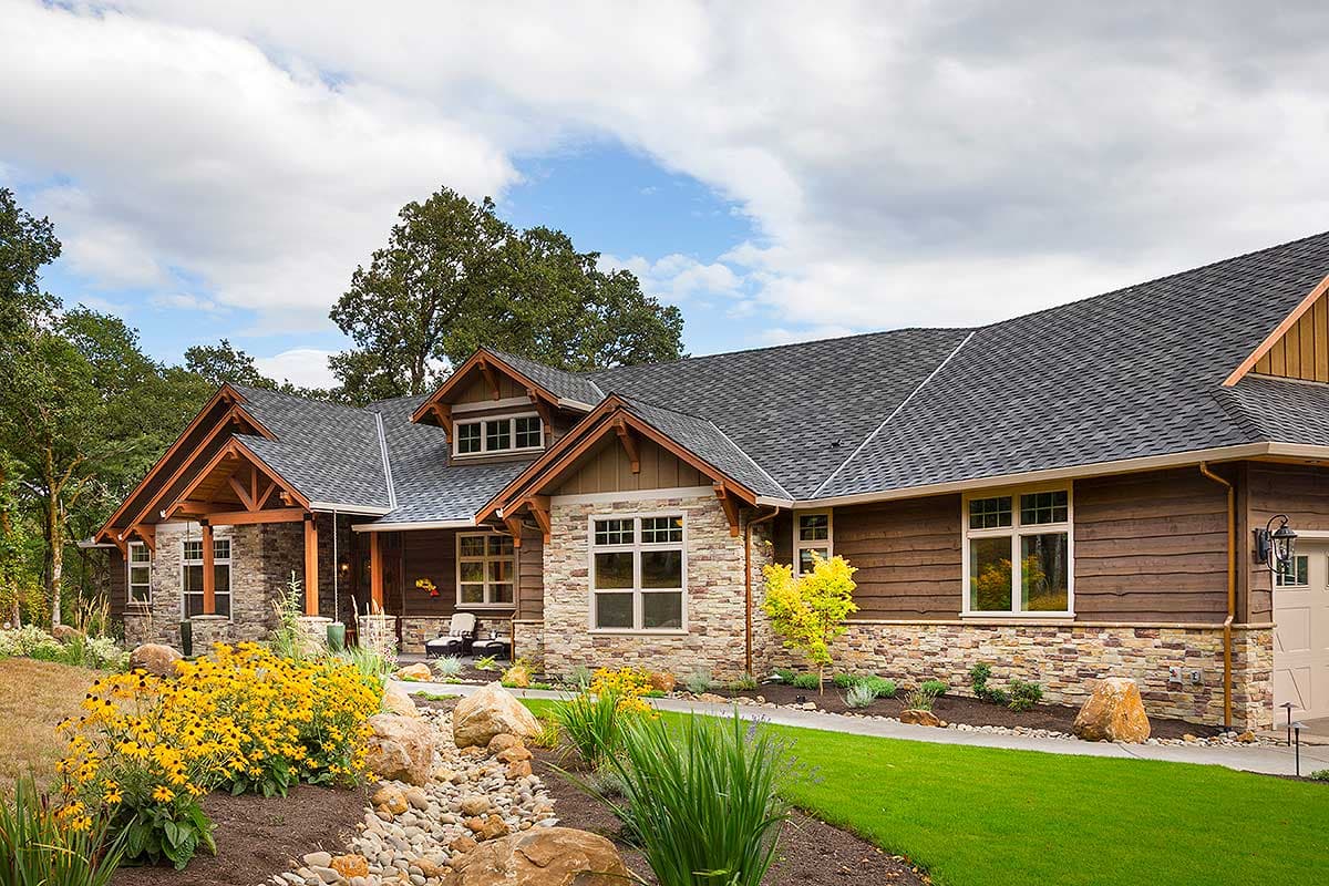 Craftsman style house plan exterior with stone and wood siding, prominent gables, dormer window, and covered porch.