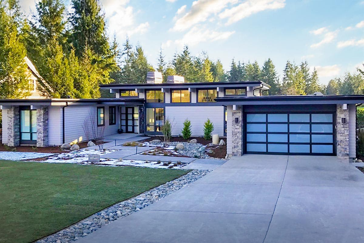 House plan exterior. Modern style, single-story home with flat roof. Features include large windows, an attached garage, and stone accents.