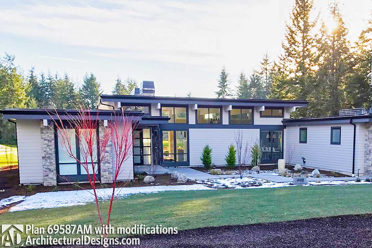 Modern house plan exterior featuring a low-pitched roof, large horizontal windows, and stone accents.