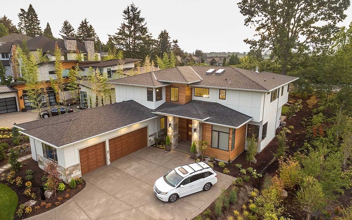 Modern house plan exterior with a two-car garage, angled rooflines, wood siding accents, and stone column entrance.