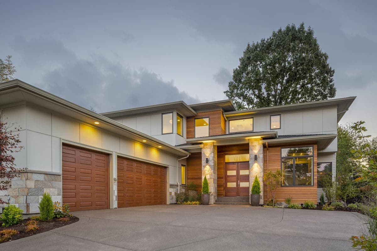 Modern house plan exterior: Two-story home with a three-car garage, wood siding, stone accents, flat rooflines, and double front doors.