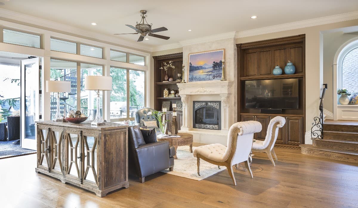 Living room with fireplace, built-in entertainment center, large windows, and double doors leading outdoors.