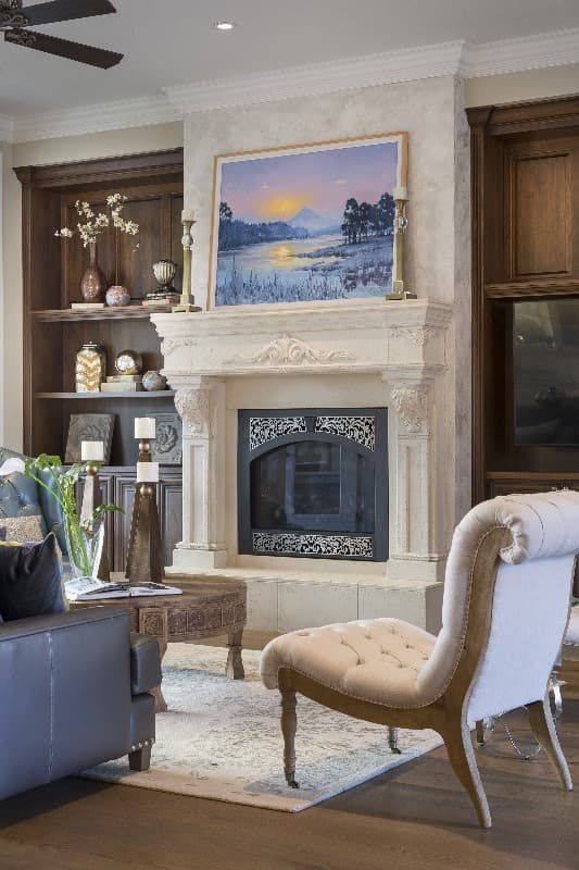 Living room with stone fireplace, built-in shelving, decorative rug, and tufted chair.