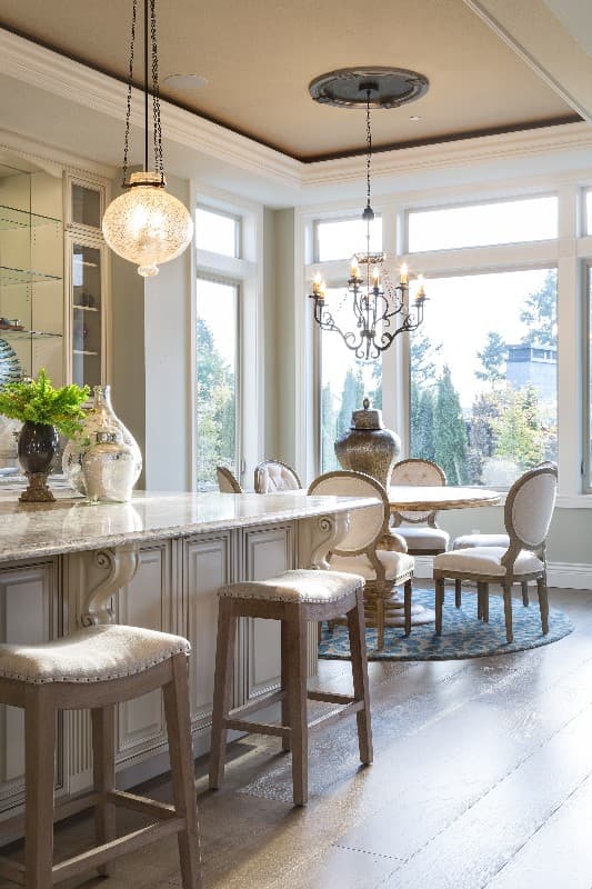 Kitchen island with bar stools and a small dining area with chairs near large windows.