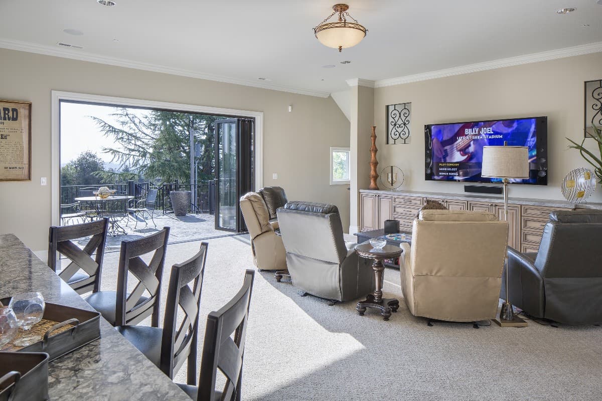 Living room with entertainment center, recliners, and bi-fold doors opening to a patio with a table and chairs.