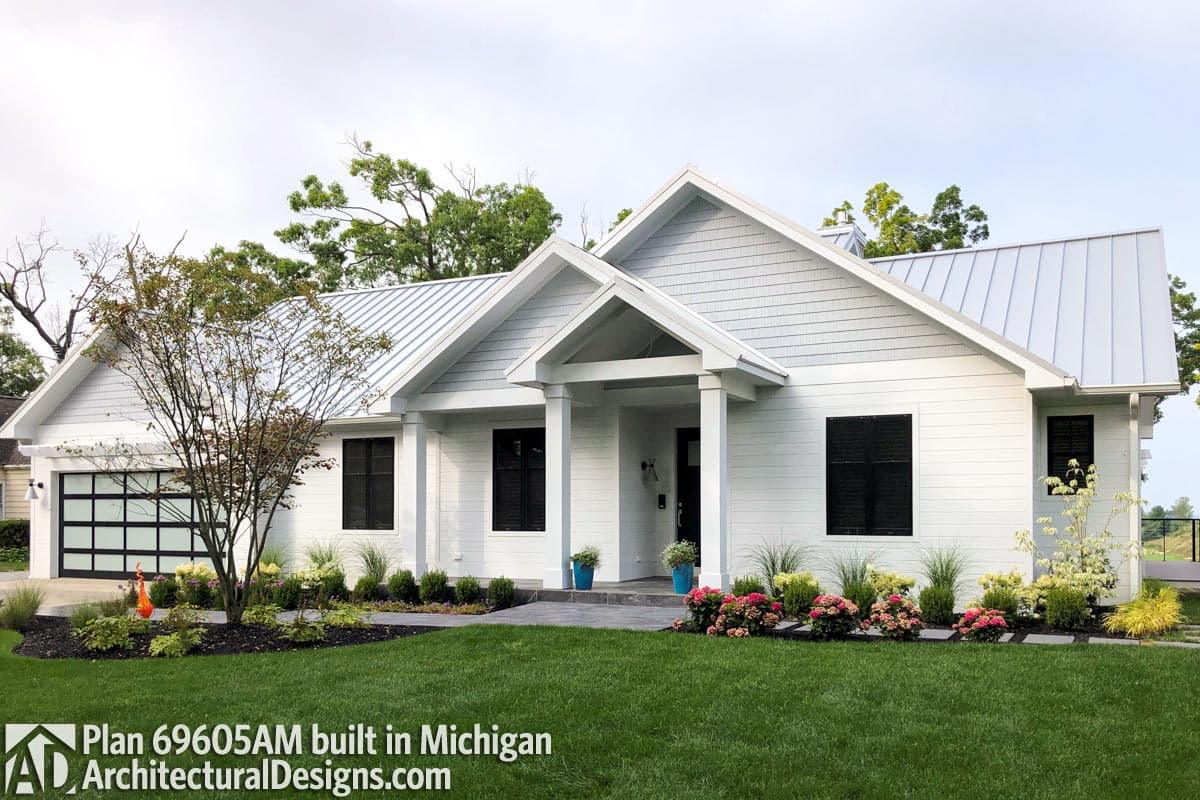 House plan exterior: Modern Farmhouse style, one-story with metal roof, prominent gables, covered entry, and glass garage door.