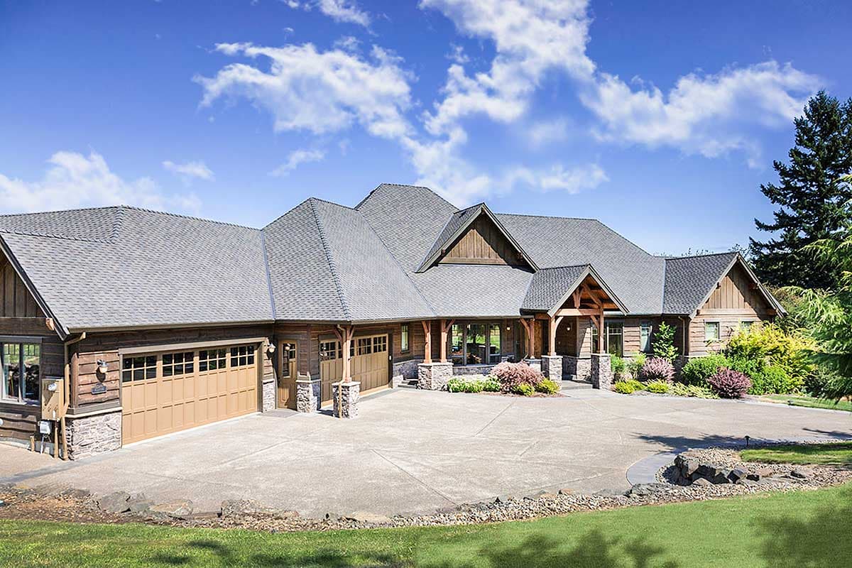 House plan exterior. Craftsman style, single-story house with gabled rooflines, exposed timber porch supports, and attached garage with stone accents.