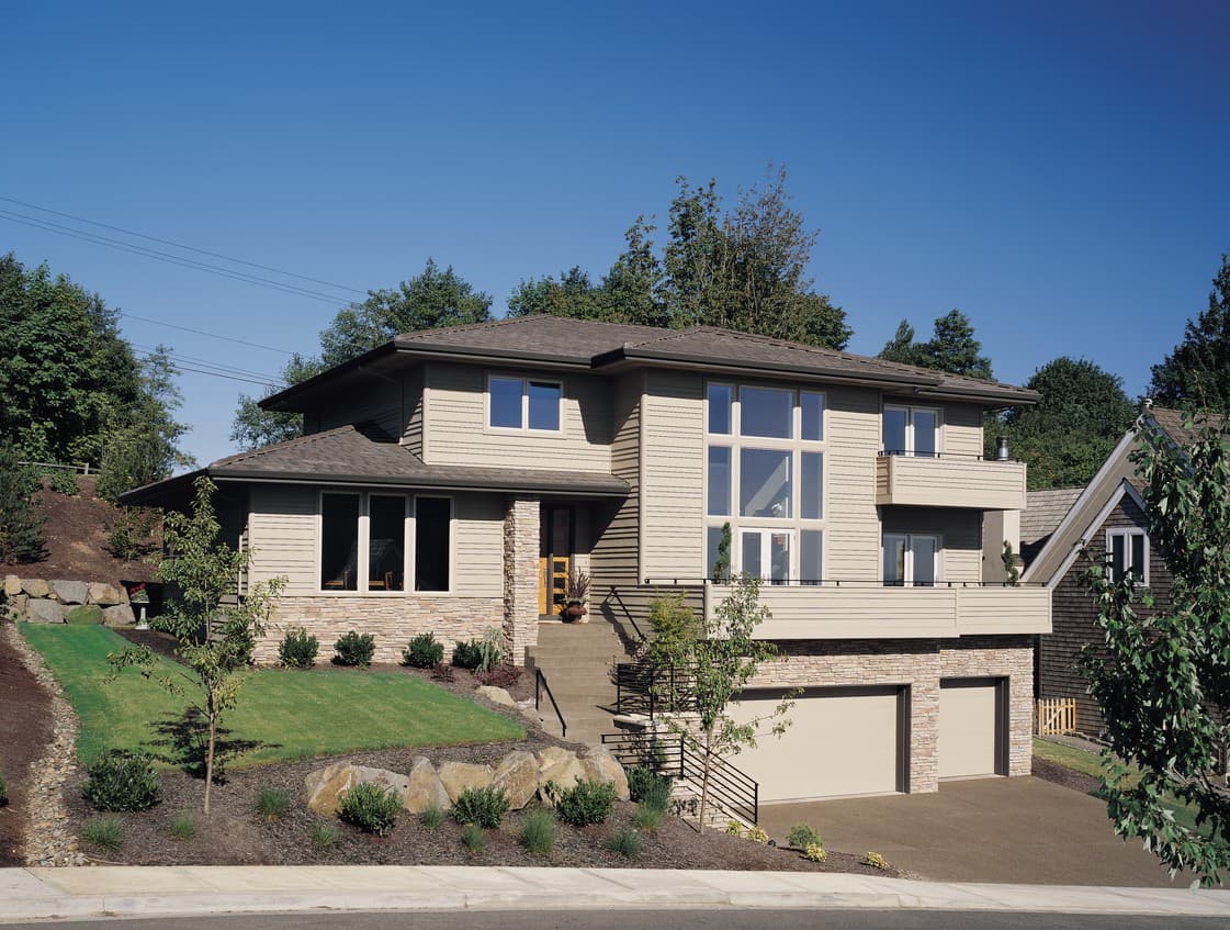 House plan exterior: Two-story modern home with stone base, large window array, and dual garage doors.