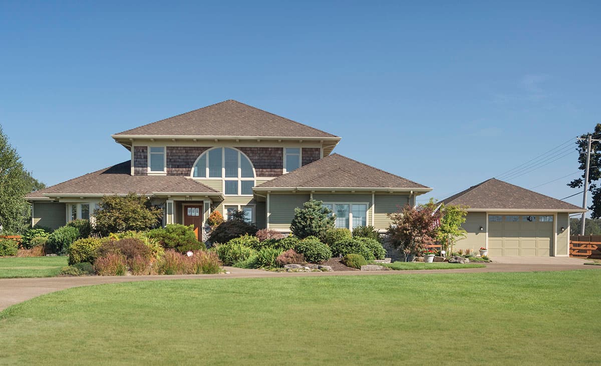 House plan exterior: Two-story home with gabled roofs, a prominent arched window, wide eaves, and a detached three-car garage.