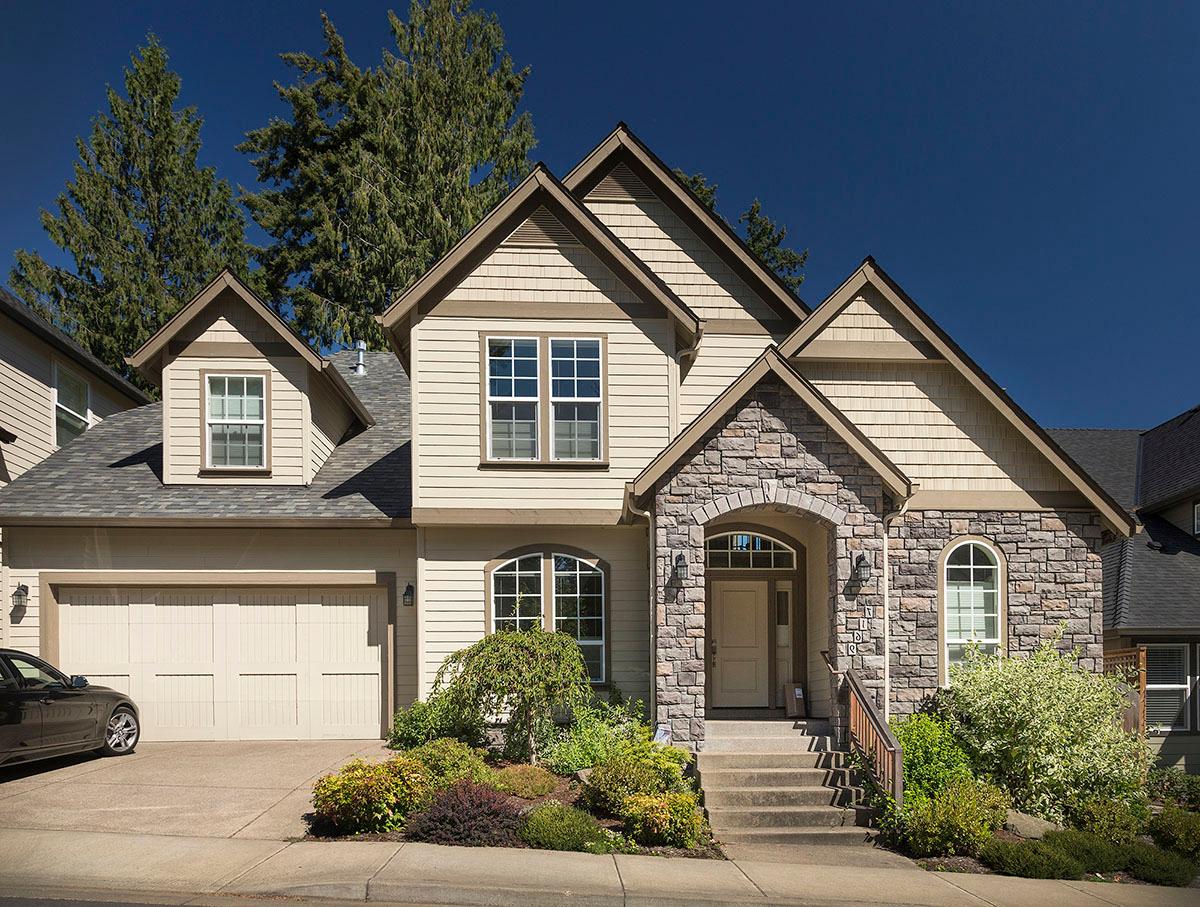 House plan exterior: Two-story home with a stone-clad arched entry, gable dormers, and a side-entry garage.