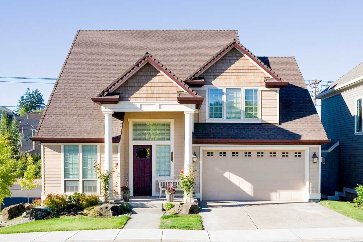 House plan exterior: Two-story home with a prominent gabled roof, covered front porch supported by columns, and a double garage.