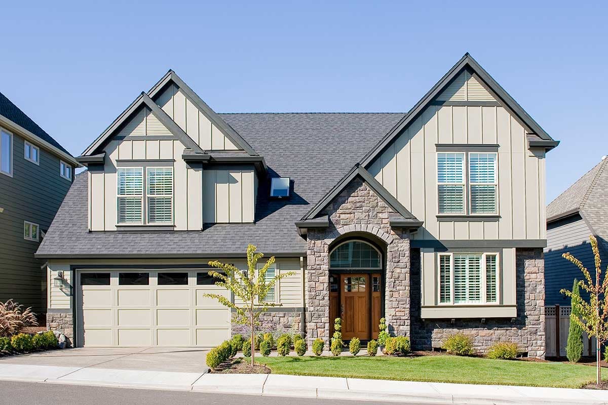 House plan exterior: two-story home with stone accents, arched entry, dual gables, and attached garage.