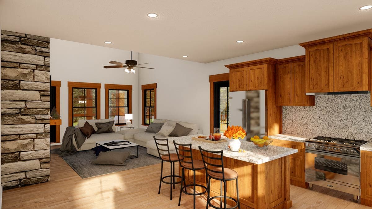 Open concept living area with stone fireplace, sectional sofa, kitchen island with bar stools, and wood cabinetry.